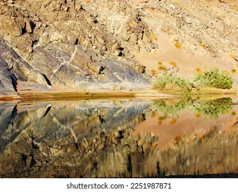 Reflection of the steep, rocky bank in the calm river, within the Fish River Canyon, Namibia - Shutterstock ID 2251987871