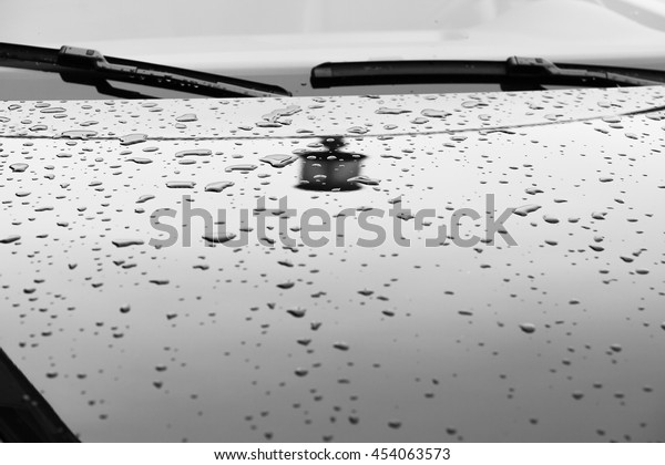 Reflection of the street lamp and raindrops\
on the hood of the car in the parking\
lot.