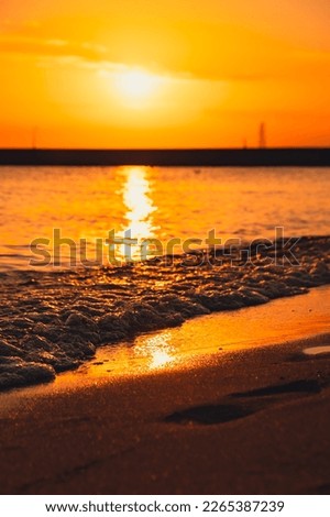 Reflection of sunlight over sea surface at sunset. Orange and gold blue sky. Scenic Gold sea. Dramatic Yellow sun coming out of the sea. Majestic summer landscape