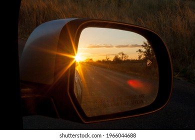 Reflection of a sunset in a rear view mirror.