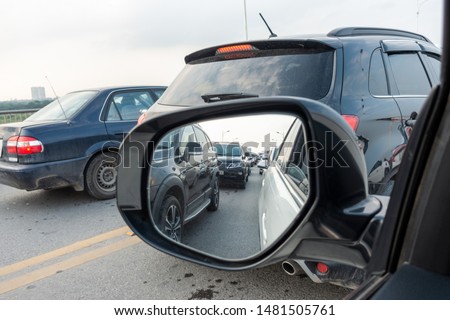 Reflection of traffic flow in left side rear view mirror at rush hour