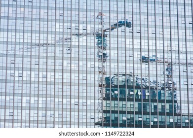 Reflection of two cranes in windows of skyscraper on a consturction site