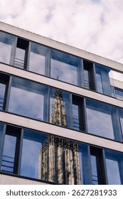 Reflection of the Ulmer Münster in the windows of a building with a cloud covered sky