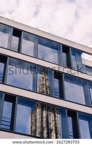 Reflection of the Ulmer Münster in the windows of a building with a cloud covered sky