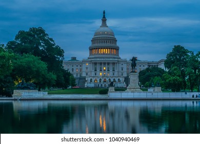 A reflection of the US Capitol Building at twilight.