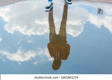 Reflection in water of man with casual style standing in bright blue sky 