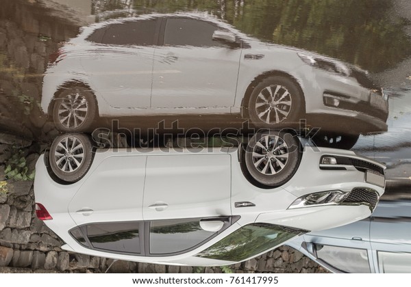 Reflection of white auto kia in the water\
in the parking lot. Moscow Russia 04. July\
2017