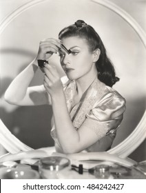 Reflection of woman in mirror applying eye make-up