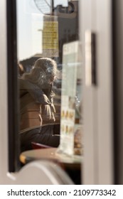 Reflection Of A Woman Smoking Outside Of A Coffee Shop.