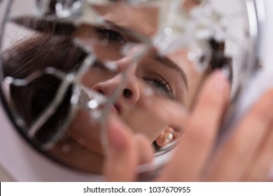 Reflection Of A Woman's Face In Broken Mirror