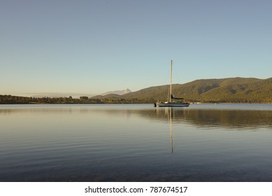 The Reflection Of Yacht And Mountain. View Of Lake Te Anua Newzealand In The Morning. 