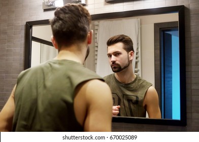 Reflection Of Young Man In Bathroom Mirror Looking On His Face