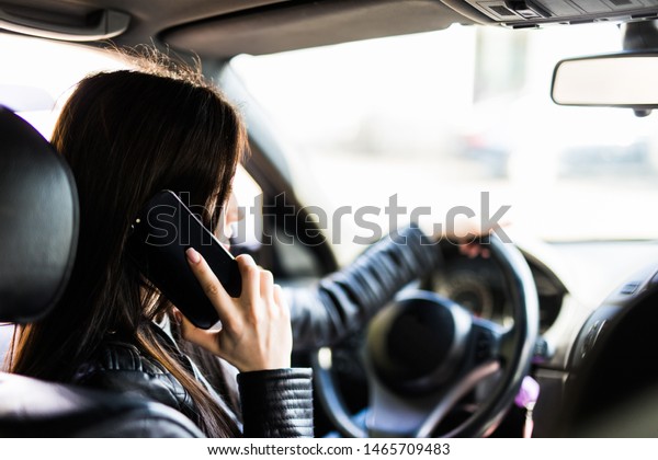 Reflection of young woman talking on a mobile\
phone in the car rear view mirror. No cell phone, while driving.\
Safe driving\
concept.