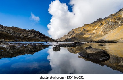 Reflections of clouds and rocks on high mountain Gosainkunda Lake in Nepal. Holy Gosainkunda is a popular trekking and religious destination in Langtang National park.