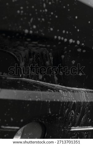 Reflections and foam on shiny bumper surface, Closeup of soap foam and reflective bubbles on bumper surface, Detailed view of bumper covered with shiny soap foam and bubbling reflections