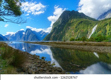 reflections of mountains in the water and a waterfall at famous milford sound,  fiordland, southland, new zealand - Shutterstock ID 1262528767