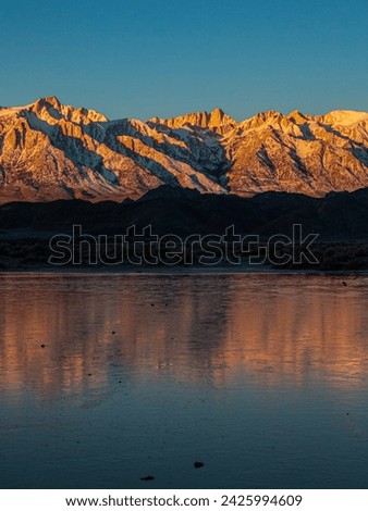 Reflections of Mt Whitney in water standing on a dry lake in the morning.