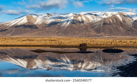 Reflections  on a rural and remote country water hole in arid tundra desert land near snow capped mountains - Powered by Shutterstock