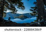 Reflective Blue Waters of Crater Lake between pine trees in summer