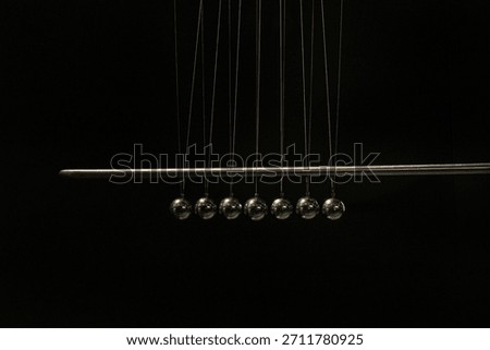 Reflective chrome balls of Newton's pendulum on a black background, scientific minimalism