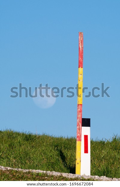 Reflective edge marker post and snow pole\
on the side of the road with rising moon in background. Traffic,\
signals and signs, road markers and safety\
concepts