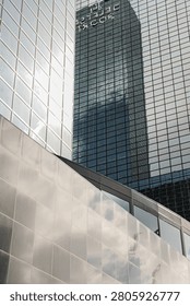 Reflective surface of a building capturing another skyscraper with visible text in Rotterdam.