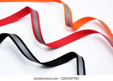 Reflective tape on a fabric basis. Orange and red, black reflective tape on a white background. Signal tape with adhesive layer. 