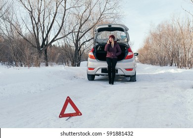 Reflective Warning Triangle Before Vehicle, An Emergency Situation On The Road In Winter, Calls For Help, Woman Talking On Cell Phone, Car Broke Down, Dangerous Winter Road Covered With Snow