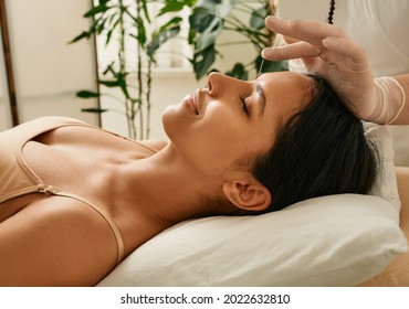Reflexologist inserts acupuncture needles into acupuncture point on female head for headaches treatment. Traditional chinese medicine, reflexology
