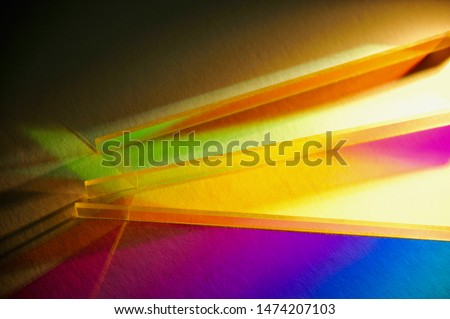 Refraction of artificial light pass through stripes of dichroic colour filter creating scattering colourful shadow on white textured paper and sparkling effect at the edge of the acrylic