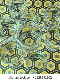 Refraction Of Light, Top View Through Water Inside Several Clear Glasses Creating Distorted Image Of Colourful Octagonal Pattern And Infinity Effect Of Circular Shapes. Visual Perception. 