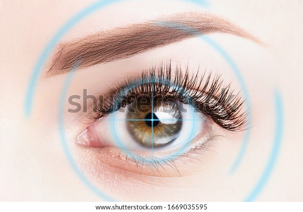 Refractive surgery, eye laser surgery\
concept. Female eye close up with blue laser\
rays.