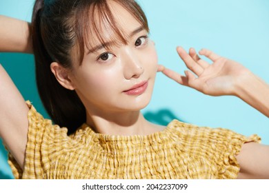 Refreshing beauty portrait of a young Asian woman on a blue background - Shutterstock ID 2042237099