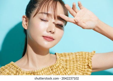 Refreshing beauty portrait of a young Asian woman on a blue background