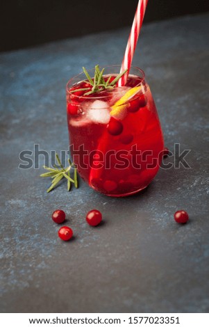 Refreshing cocktail with sparkling water, vodka and iced cranberry on a black stone tray. Dark background.
