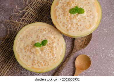 Refreshing Coco Melon Dessert Recipe With Tapioca Served In Melon Shells On Top Of A Table With Wooden Spoons