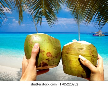 Refreshing Coconut Cocktail In Woman And Man Hand. Coconut Water Drink On The Maldives Beach. Cheers!  Toast.