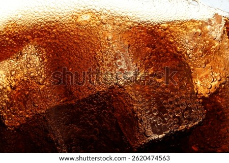 Refreshing cola with ice as background, macro view