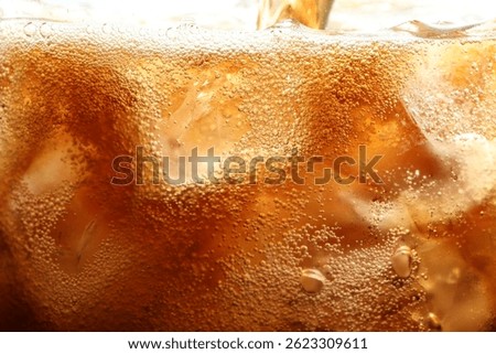Refreshing cola with ice as background, macro view
