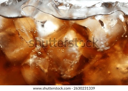 Refreshing cola with ice as background, macro view