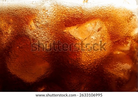 Refreshing cola with ice as background, macro view