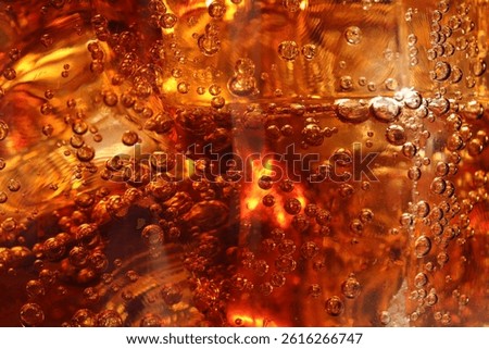 Refreshing cola with ice cubes as background, macro view
