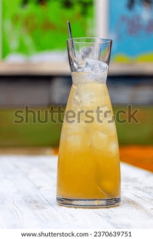 Refreshing cold green lemonade in a carafe on the table on the background of nature. Fresh drinks whith ice. Lemonade with lemon, lime and herbs
