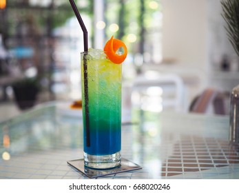A refreshing colorful mocktail glass of iced orange blue which is drink mixed with orange, honey, lime and blue curacao decorated with sliced of mandarin orange peel. Selective focus, blur background.