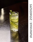 A refreshing and crisp cucumber gin cocktail, served in a tall glass with ice and garnished with fresh mint