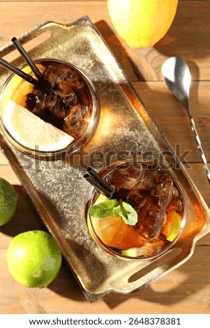 Refreshing Cuba libre cocktail with mint on wooden table, flat lay
