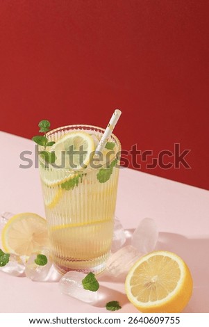 Refreshing Drink with Ice, Lemon, and Mint. Cold Lemonade on Pink Red Background