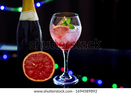 refreshing elegant cocktail made with grapefruit and wine at the bar on black background with lights