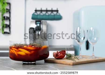 Refreshing fruit punch served in a clear bowl with pomegranate and herbs on a modern kitchen countertop 