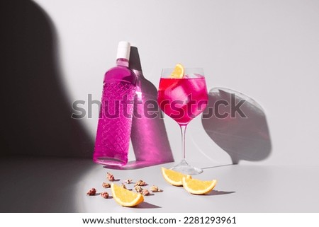 Refreshing glass of pink gin and tonic garnished with orange 